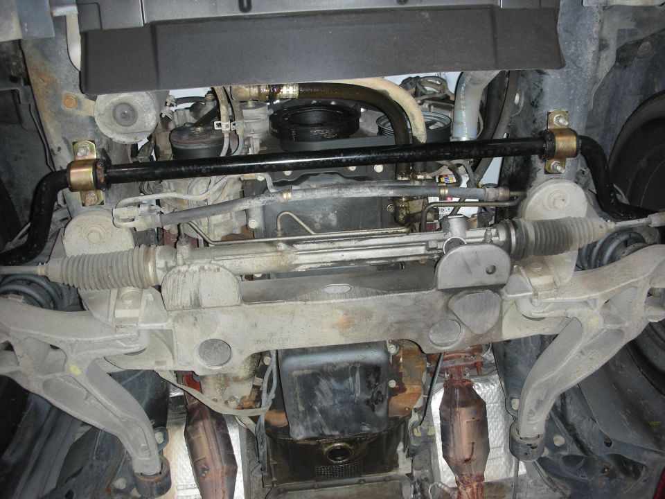 2004 Ford Crown Victoria underbody showing a black sway bar with gold bushings and the steering rack