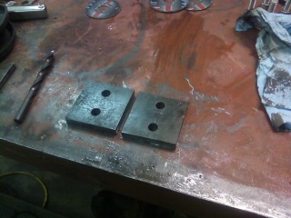 1995 Ford Bronco - Metal parts and tools are laid out on a workbench, possibly for automotive repair or fabrication.