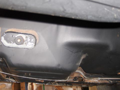 1971 Chevrolet Camaro - Underside view of a vehicle fuel tank showing a fuel line and some surface rust.
