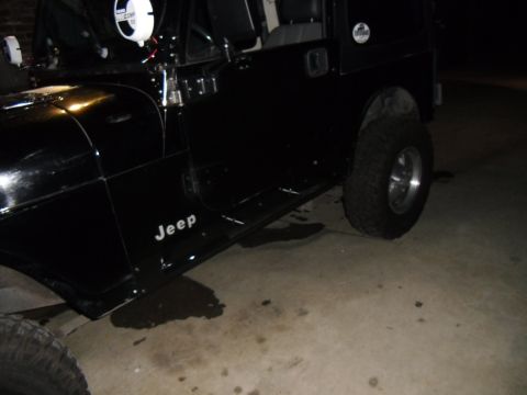 1992 Jeep Wrangler - A black Jeep Wrangler is parked on a concrete surface, with a puddle of liquid beneath it.
