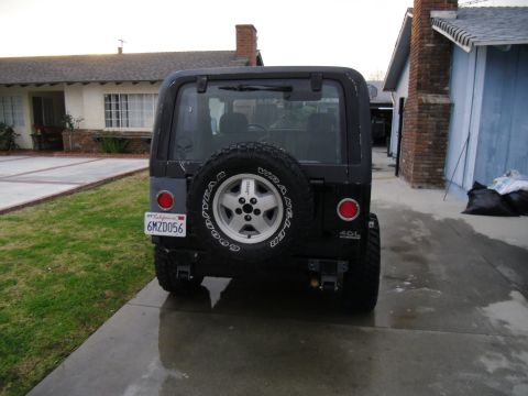 1992 Jeep Wrangler - Rear view of a black Jeep Wrangler parked in a driveway next to a house.
