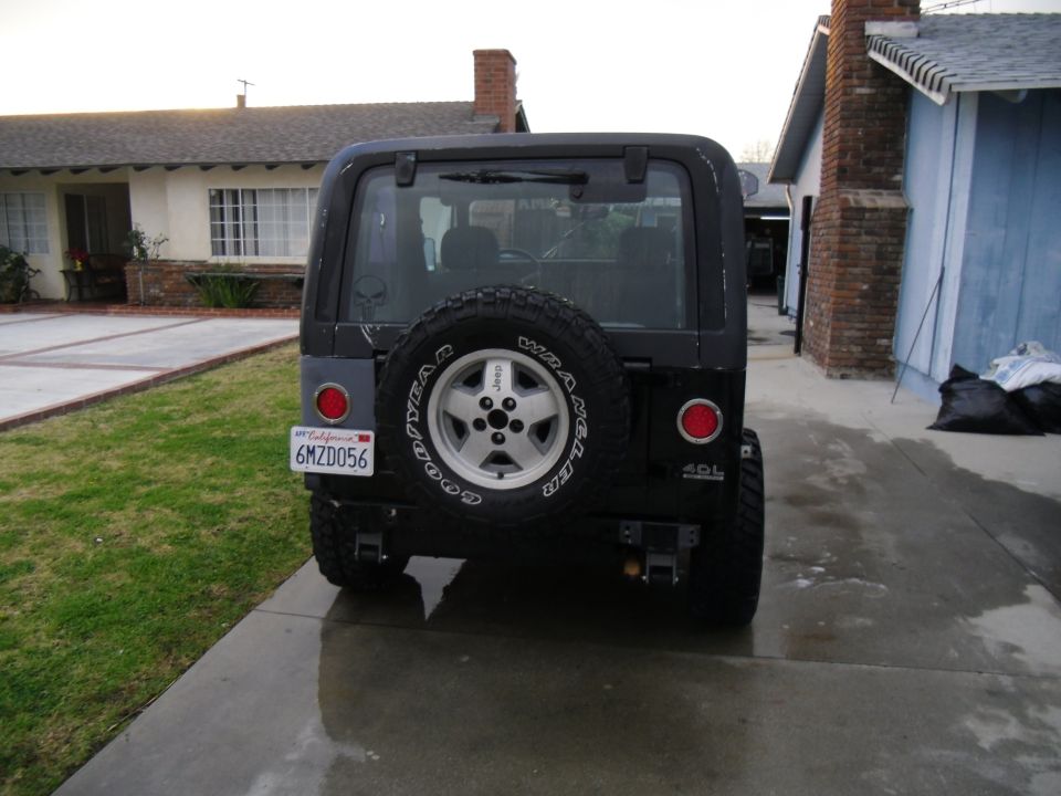 Black Jeep Wrangler with spare tire on rear, California license plate 6MZD056, and 4.0L badge