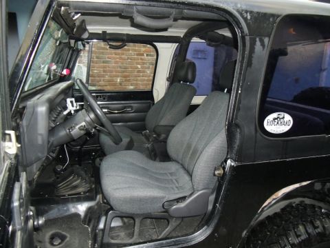 1992 Jeep Wrangler - The interior of a black Jeep is shown, the seats, dashboard, and a "Rockhard" sticker on the rear window.