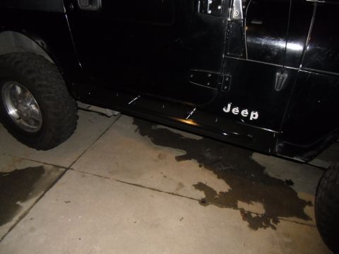 1992 Jeep Wrangler - A black Jeep Wrangler is parked on a concrete surface with visible water stains underneath.