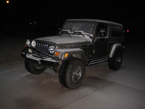 2005 Jeep Wrangler - A black Jeep Wrangler Rubicon is covered in a light dusting of snow, parked outdoors at night.