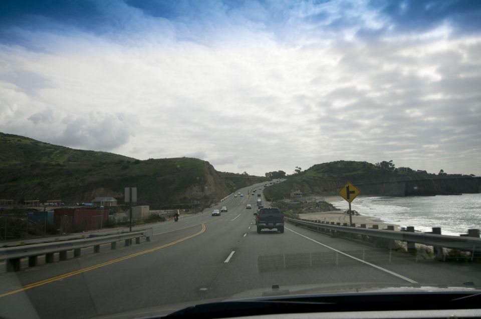 Dark SUV driving on a highway next to the ocean