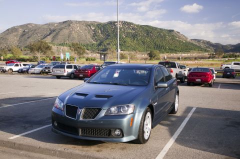 2006 Cadillac STS - A blue sedan with distinctive hood scoops is parked in a lot with mountains in the background.