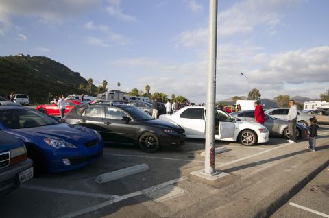 2006 Cadillac STS - A gathering of vehicles and people in a parking lot with RVs and hills in the background.