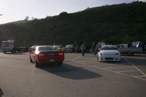2006 Cadillac STS - Several cars and people are gathered in a parking lot under a grassy hill.