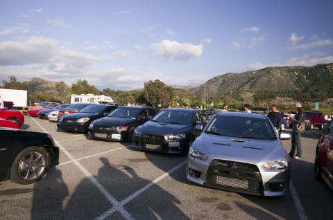 2006 Cadillac STS - Cars parked in a lot with mountains in the background under a partly cloudy sky.