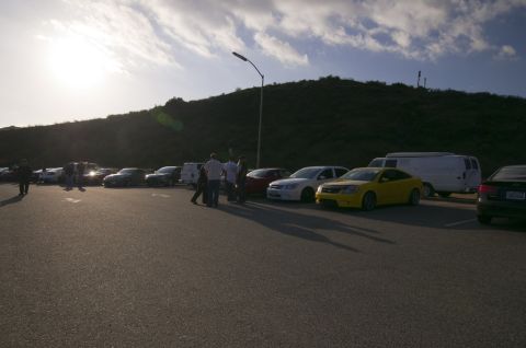 2006 Cadillac STS - Cars and people gathered in a parking lot under a cloudy sky.