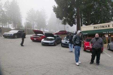 2006 Cadillac STS - Several cars are gathered in a parking lot on a foggy day, with people standing around.