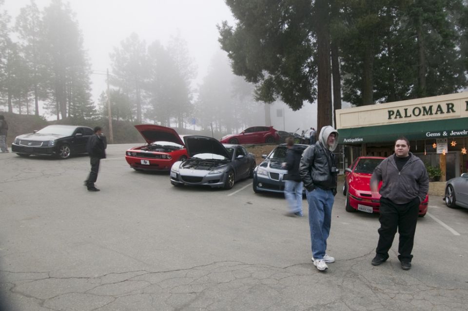 Black sedan parked in a lot with other cars and people