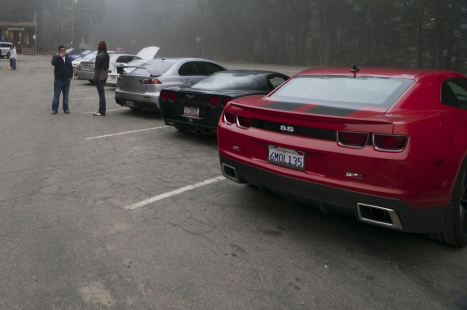 Red Chevrolet Camaro SS with black racing stripes and license plate 6MDL135 parked in a lot