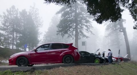 2006 Cadillac STS - Several cars are parked on a foggy roadside, with a red hatchback in the foreground.