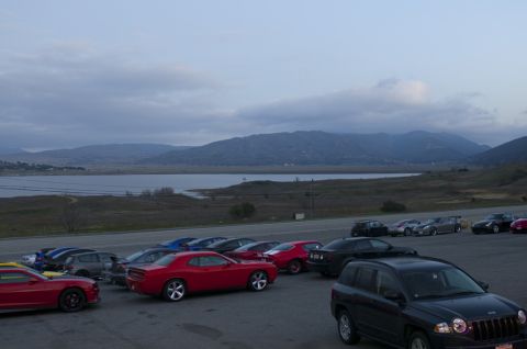 2006 Cadillac STS - A collection of cars are parked in a lot overlooking a lake and distant mountains under a cloudy sky.