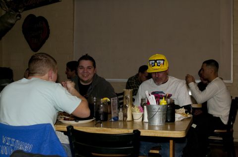 2006 Cadillac STS - Several people are gathered around a table in a dimly lit restaurant, some eating and others talking.