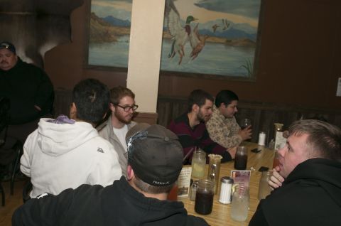 2006 Cadillac STS - Several individuals are seated at a table, engaged in conversation in a restaurant setting.