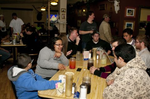 2006 Cadillac STS - A group of people are seated around tables in a casual dining establishment, with some standing in the background.