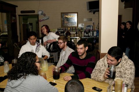 2006 Cadillac STS - People gathered at tables inside a bar, with a shelf of bottles visible in the background.