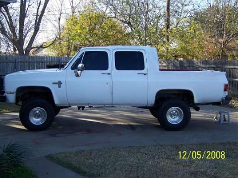 1990 Chevrolet Suburban - This lifted, four-door pickup truck is shown from the side in a driveway.