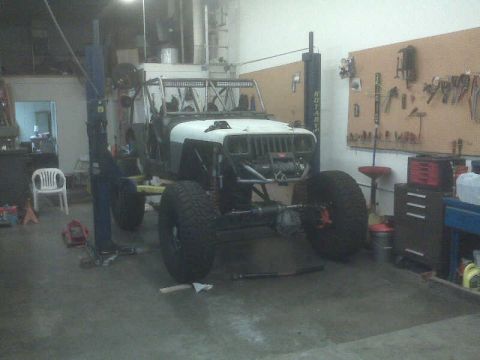 1994 Jeep YJ - A Jeep Wrangler is undergoing modifications in a workshop, with its engine and suspension components visible.