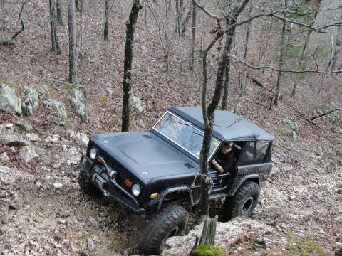 1967 Ford Mustang - This black off-road SUV is shown navigating a challenging rocky terrain on a wooded trail.