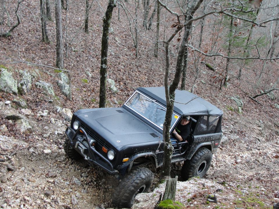 Black off-road SUV with a winch on the front bumper navigating a rocky incline