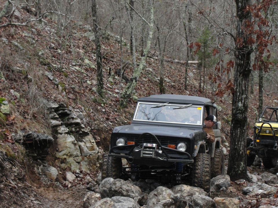 Black 1966 Ford Bronco navigating a rocky off-road trail