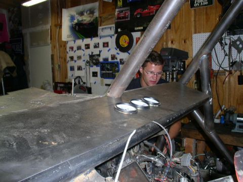 1979 Ford Bronco - A person works on a custom vehicle's interior, surrounded by garage tools and posters.