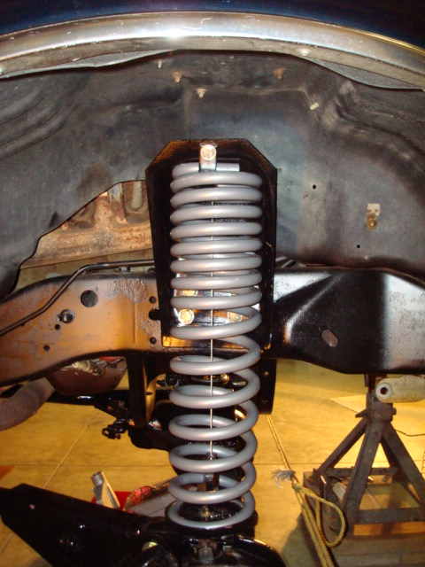 1995 Ford Bronco - This image shows a close-up view of a vehicle's suspension system, focusing on the coil spring and its mounting hardware.