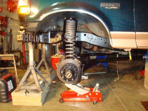 1995 Ford Bronco - Front suspension components are removed from a green 1995 Ford Bronco undergoing repairs.