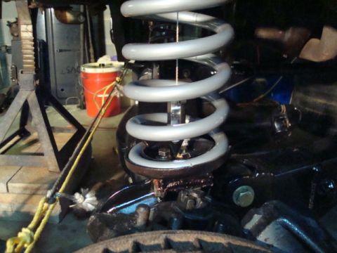 1995 Ford Bronco - Close-up view of a vehicle's suspension system, showing a large coil spring and associated mechanical components.