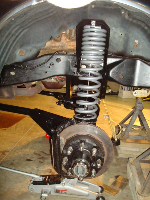1995 Ford Bronco - Close-up view of a vehicle's front suspension and brake system, showing a coil spring and disc brake assembly.