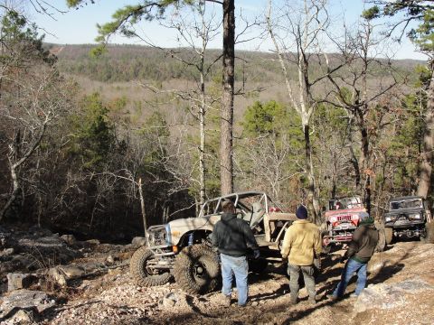 1967 Ford Mustang - Several off-road vehicles are parked on a rocky trail surrounded by trees and hills.