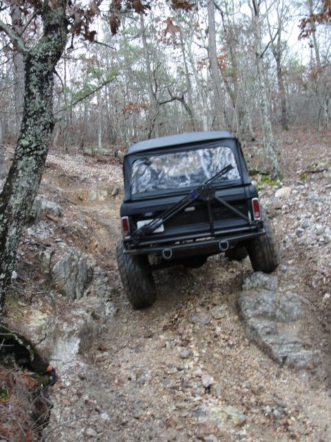 1967 Ford Mustang - This black SUV is shown from behind as it drives on a rough, rocky path through a forest.