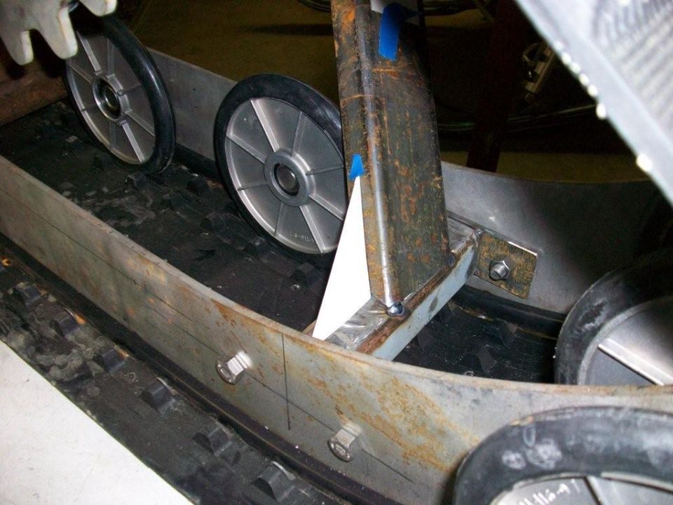 Rubber track conversion with gray idler wheels and rusty steel suspension frame