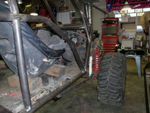 1979 Ford Bronco - Custom off-road buggy under construction in a workshop, showing interior and large tire.