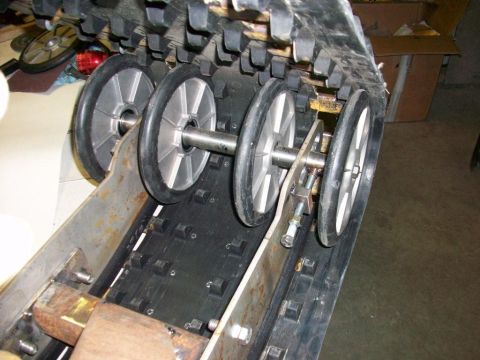 1987 Suzuki Samurai - Close-up view of a snowmobile track assembly with multiple wheels and a metal support structure.