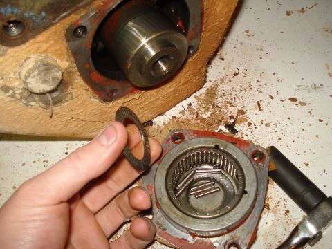 1991 Ford Bronco - A hand holds a wavy washer above a disassembled drivetrain component with visible roller bearings.