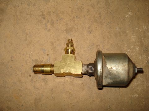 1985 Ford F-150 - A brass T-fitting with a pressure sensor attached is shown against a textured background.