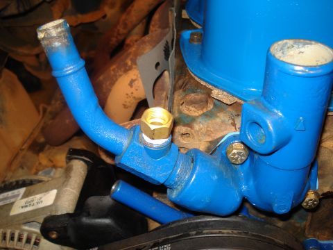1985 Ford F-150 - Close-up view of engine coolant plumbing, showing blue painted pipes and brass fittings attached to the engine block.