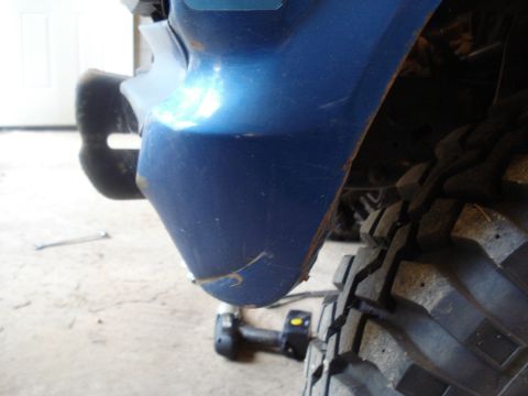 1985 Ford F-150 - Close-up of a blue truck's fender and tire, showing wear and tear.