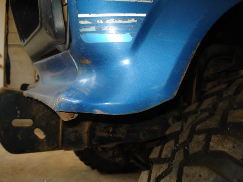 1985 Ford F-150 - Close-up of a blue truck's fender and tire, showing wear and a stripe detail.