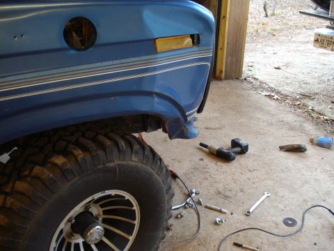 1985 Ford F-150 - Front fender and wheel of a 1985 Ford F-150, with tools scattered nearby.