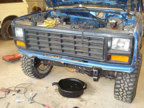 1985 Ford F-150 - A blue Ford F-series truck is undergoing maintenance in a garage, with tools and an oil pan visible.