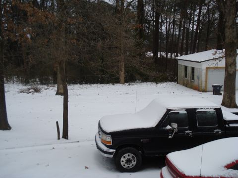 1994 Ford F-350 - A black pickup truck sits covered in snow in a residential yard next to a garage.