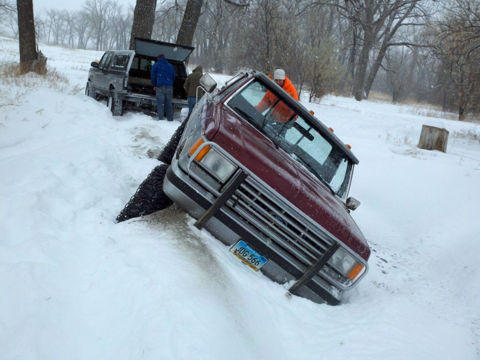 Maroon pickup truck with a brush guard stuck in snow, front view