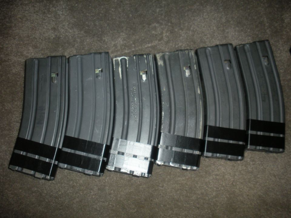 Six AR-15 magazines with black tape around the base