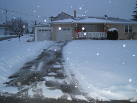 2004 Aston Martin Virage - A house with a snowy driveway and two garage doors, decorated for Christmas.